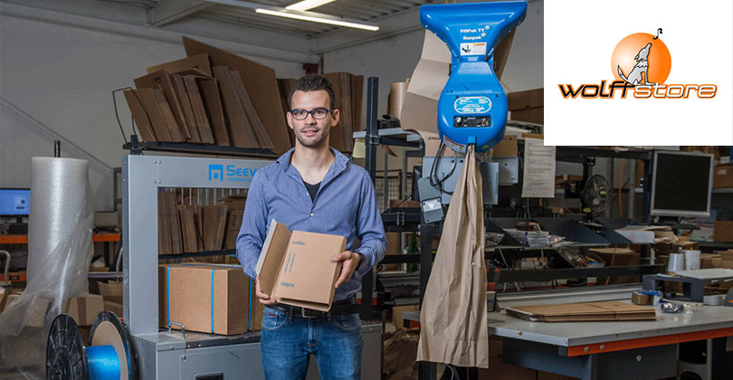 Ein Mitarbeiter von Wolffstore steht im Verpackungslager neben einem Knüllpapier-Spender